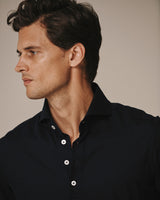 Close-up of a male model wearing the navy Piqué Polo Shirt.