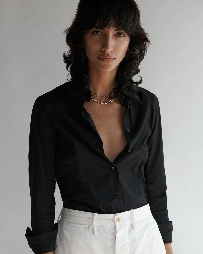 Female model wearing the Lisette Stretch Poplin Shirt and white pants.