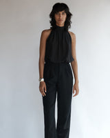 Female model wearing the Hailey Silk Halter Top and black pants.