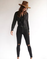 Female model wearing the Lilly Silk Bow Blouse, black jeans, and hat.